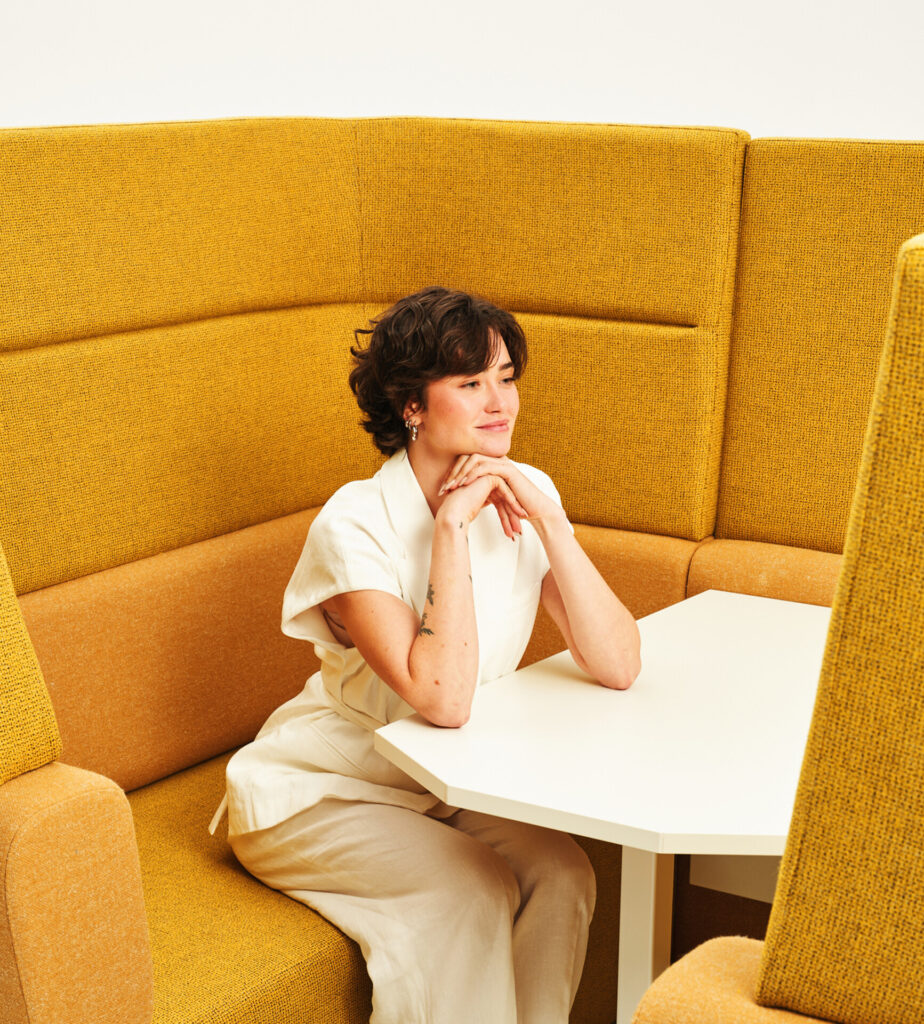 Woman seated at a white table inside a modular acoustic meeting booth