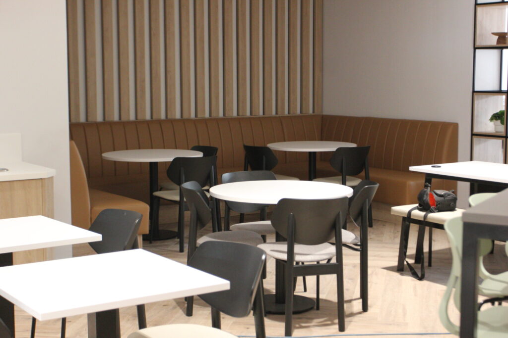 Office breakout area with modular seating, round tables, and chairs