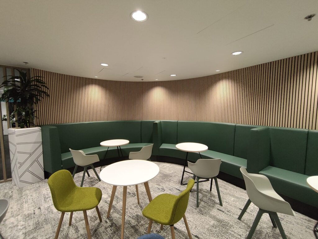 Office breakout area with curved modular seating, round tables, and chairs