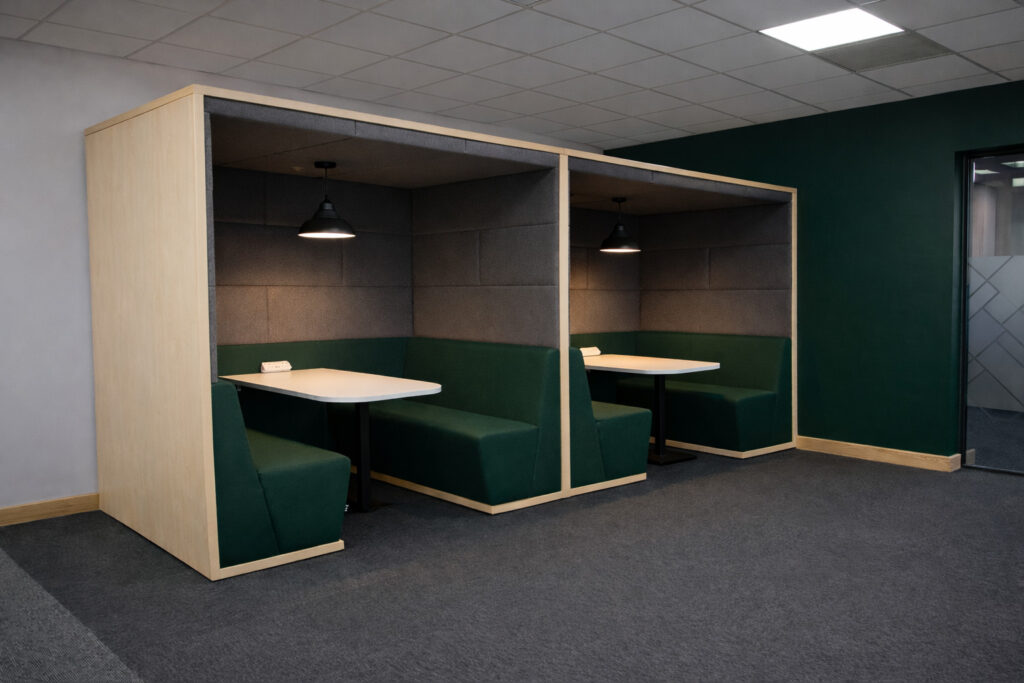 Two Session meeting booths with green banquette seating and tables in an office breakout area