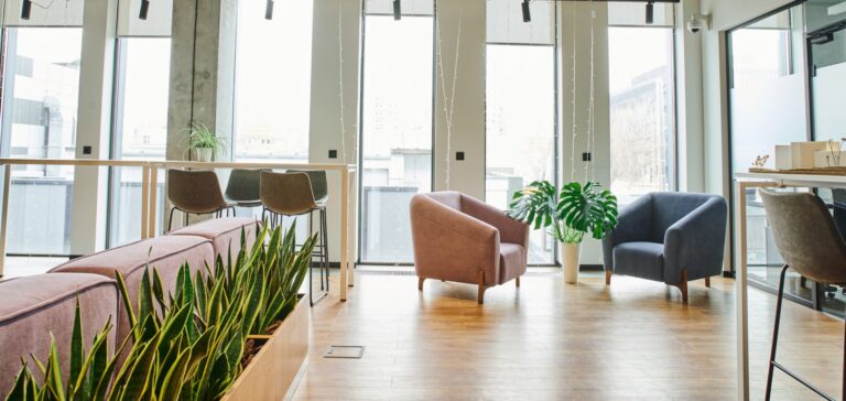 Modern office breakout area with modular seating, armchairs, and plants